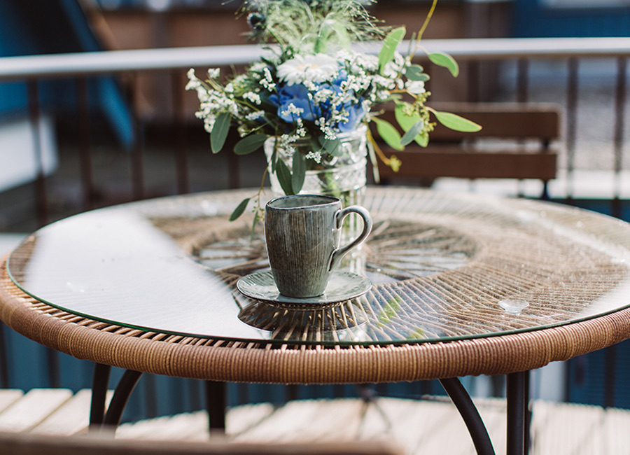 Kaffeetasse und Blumenstrauß auf einem Balkontisch