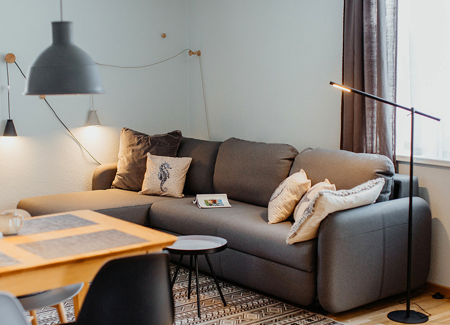 Wohnzimmer mit grauem Sofa, Kissen und Stehlampe